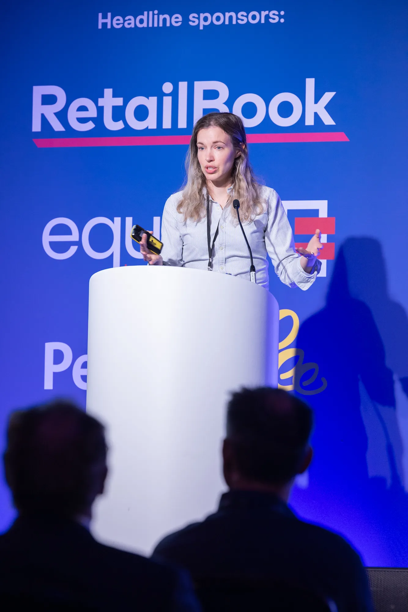 A speaker presenting from the podium in front of the headline sponsor wall